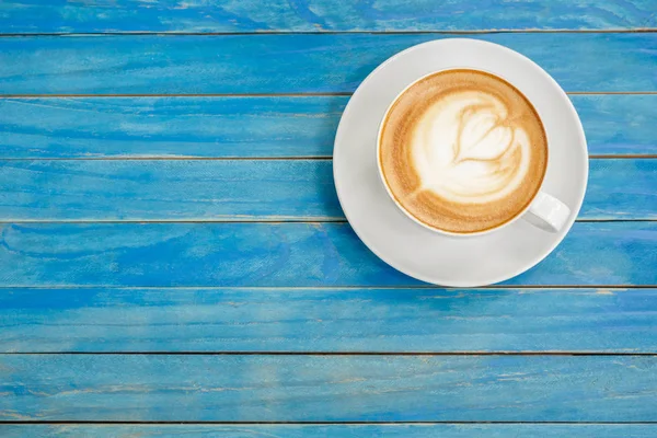 Von oben heißen Latte-Kaffee in weißer Tasse auf blauem Vintage-Holz ta — Stockfoto