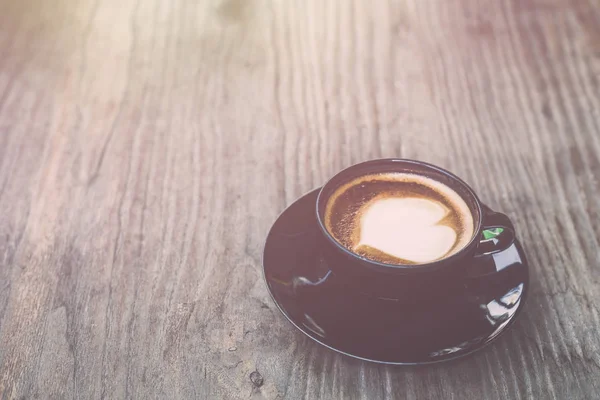 Heißer Latte-Kaffee in schwarzer Tasse auf grauem Holztischhintergrund. v — Stockfoto