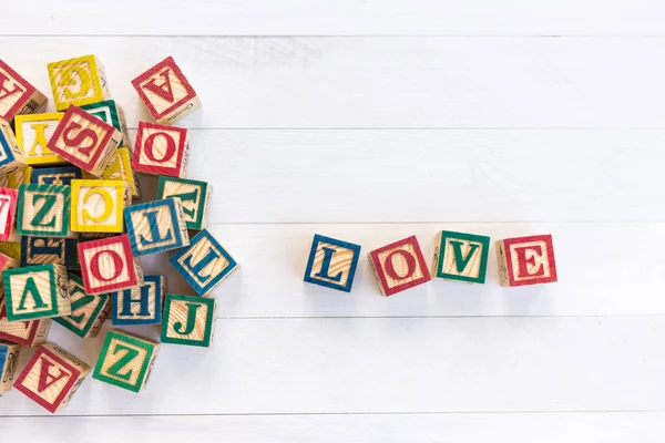 LOVE escribir en bloque de alfabeto de madera sobre fondo de madera blanco . — Foto de Stock