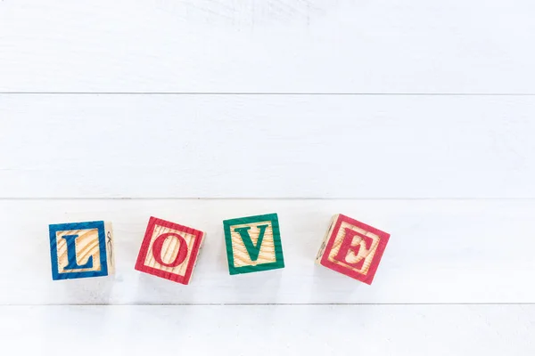 LOVE escribir en bloque de alfabeto de madera sobre fondo de madera blanco . — Foto de Stock