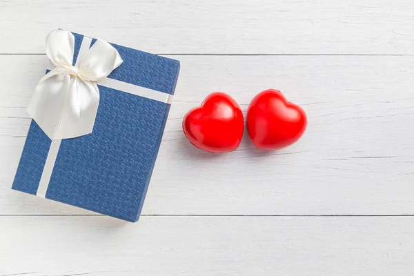 Top vue coeur rouge et boîte cadeau avec ruban sur plan en bois blanc — Photo
