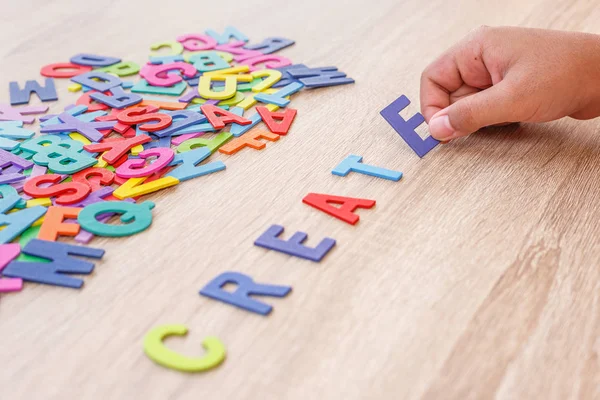 Colorful wooden alphabet and word "CREATE", Hand sort on E. Top — Stock Photo, Image