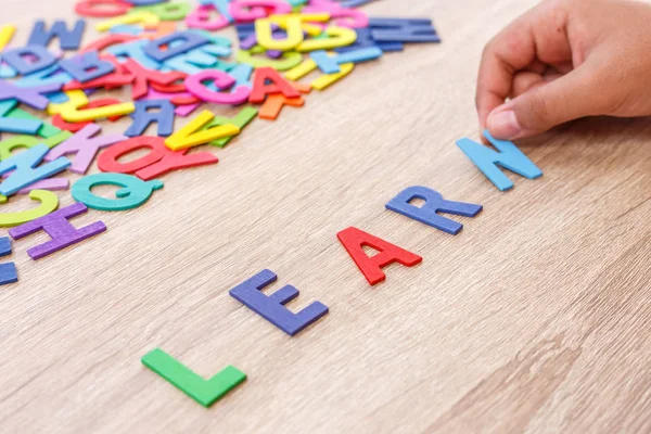 Colorato alfabeto in legno e parola "IMPARARE", ordinamento a mano su N. Top v — Foto Stock