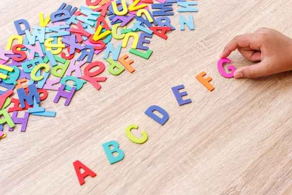 Farbenfrohes Holzalphabet und Handsortierung auf z. B. Draufsicht auf grauer — Stockfoto