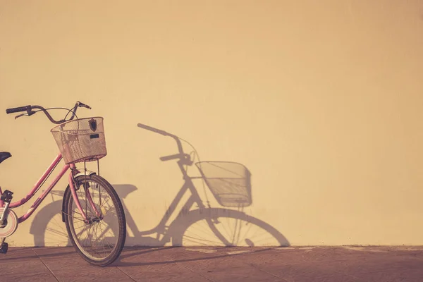 Bicycle parked at morning time beside the wall and shadow with a — Stock Photo, Image