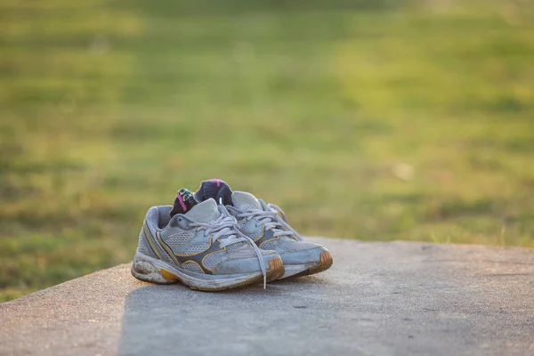 Par de zapatos deportivos grises en suelo de cemento en el parque — Foto de Stock