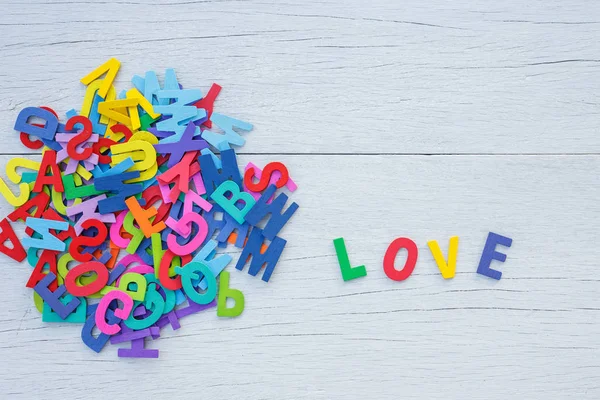 Alfabeto di legno colorato e parola LOVE. Vista dall'alto su legno bianco — Foto Stock