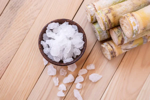 Rock sugar and sugar cane on wooden table background — Stock Photo, Image