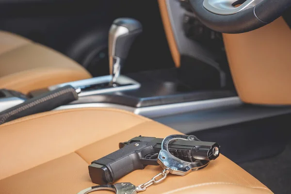 Black gun and handcuff inside the car. For violence on the road — Stock Photo, Image