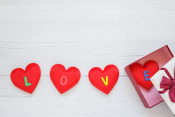 Forme de coeur rouge avec mot d'amour dans une boîte cadeau avec ruban sur blanc — Photo
