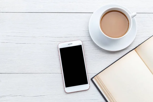 Vista superior del café, smartphone y libro vacío en la mesa de madera blanca — Foto de Stock