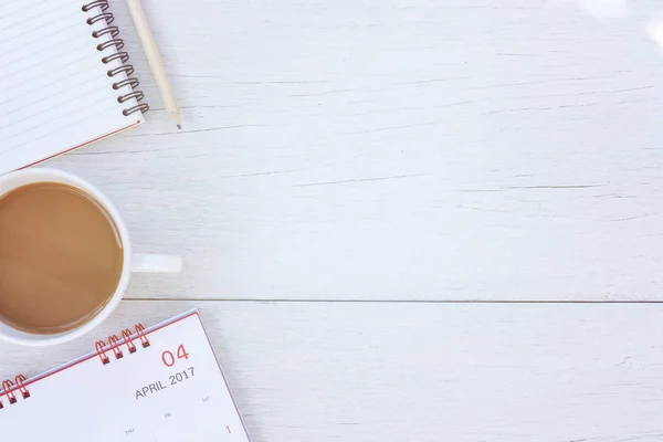Top ver livro de notas, calendário e xícara de café em tabl de madeira branca — Fotografia de Stock