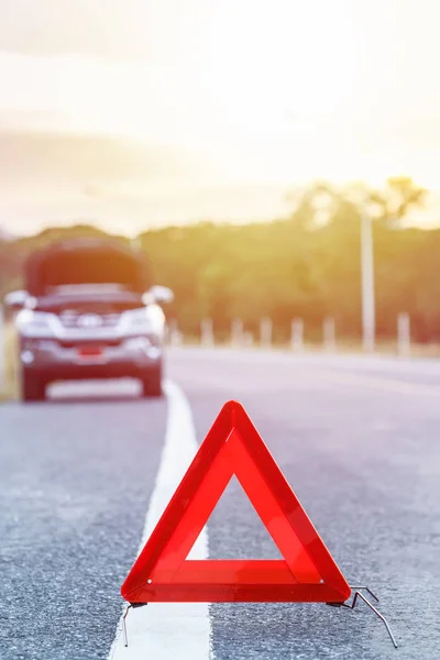 Красный знак аварийной остановки и сломанная серебристая машина на дороге — стоковое фото