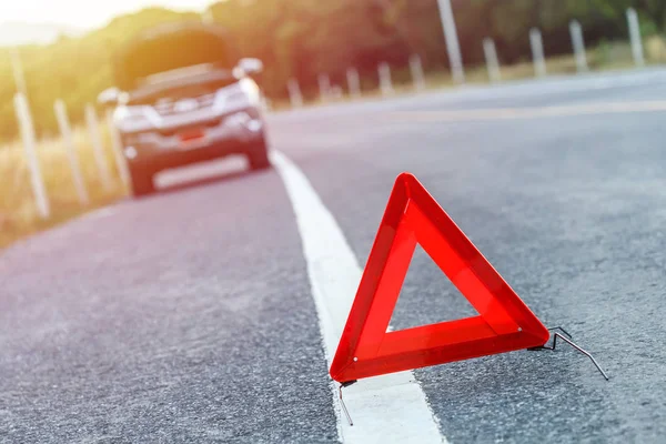 Червоний знак аварійної зупинки і зламаний срібний автомобіль на дорозі — стокове фото