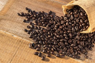 Ahşap masa küçük torba içinde kavrulmuş kahve çekirdekleri. Açık ateş etme