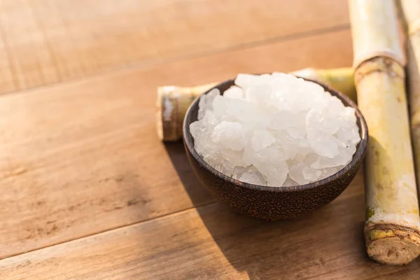 Açúcar de rocha e cana-de-açúcar sobre fundo mesa de madeira com sunlig — Fotografia de Stock