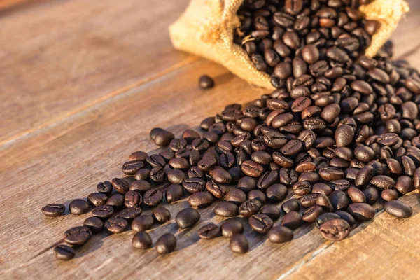 Roasted coffee beans in small sack on wooden table. Outdoor shoo — Stock Photo, Image