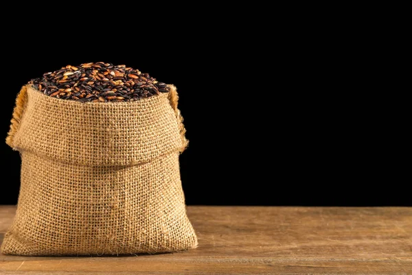 Arroz pegajoso preto tailandês em pequeno saco na mesa de madeira. Isolados — Fotografia de Stock