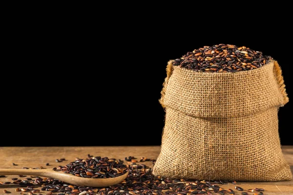 Arroz negro tailandés pegajoso en un pequeño saco sobre una mesa de madera. Aislado o —  Fotos de Stock