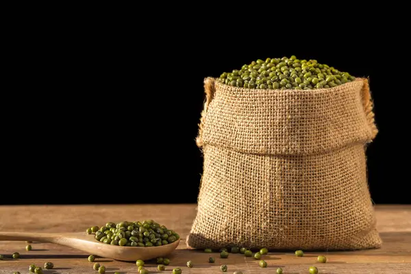 Mung beans in small wooden sack on wooden table. Isolated on bla — Stock Photo, Image