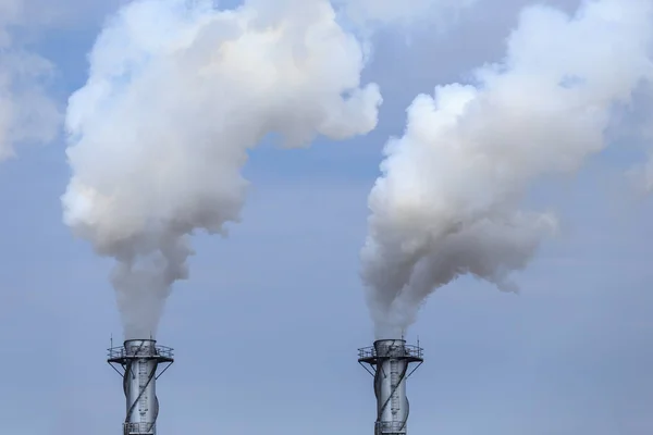 Белый промышленный пар на заводе на голубом небе — стоковое фото