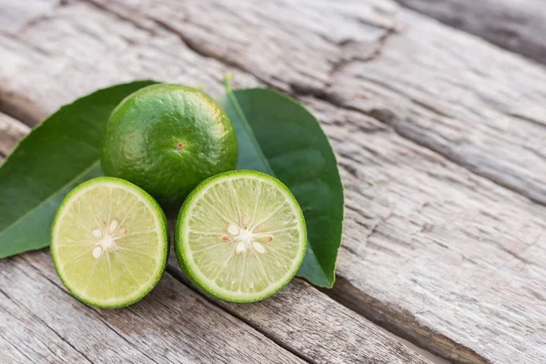 Fatia de limão fresco verde no fundo da mesa de madeira — Fotografia de Stock