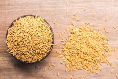 Tay sarı çeltik pirinç ahşap kase üzerinde ahşap tahta backgr koymak