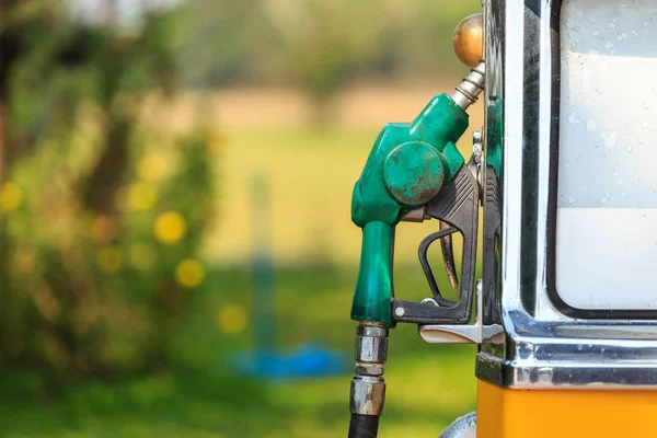 Viejo de la boquilla de combustible verde en la gasolinera en desenfoque verde —  Fotos de Stock