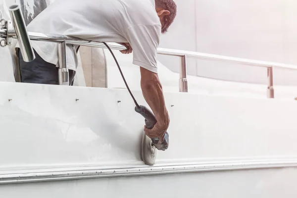 Manutenção de iates. Um homem polimento lado do barco branco no — Fotografia de Stock