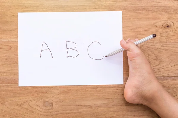 Woord "Abc" in white paper schrijven door rechter voet van handicap pers — Stockfoto