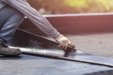 Group of worker installing tar foil on the rooftop of building.  clipart