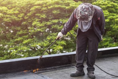 Group of worker installing tar foil on the rooftop of building.  clipart