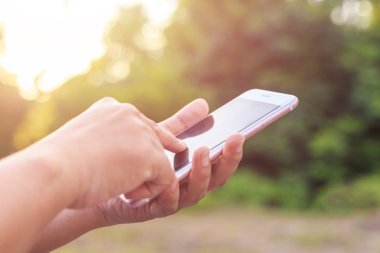 Elini tutarak veya yeşil bulanıklık ve sunl smartphone kullanarak kadının