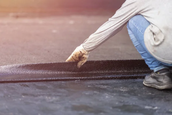 Gruppo di lavoratori che installano fogli di catrame sul tetto dell'edificio . — Foto Stock