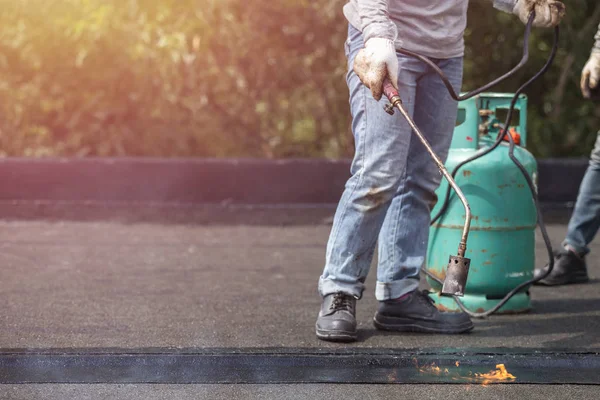 Grupp av arbetstagare installera tjära folie på taket av byggnaden. — Stockfoto