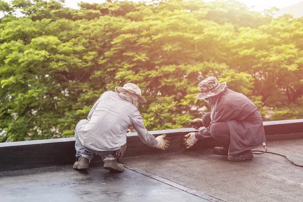 Группа рабочих, устанавливающих смоляную фольгу на крыше здания . — стоковое фото