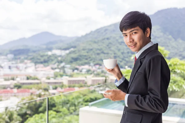 Jovem asiático empresário beber café. De pé no terraço — Fotografia de Stock