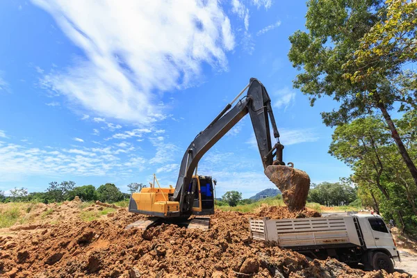 Excavatrice creuser pour déplacer le sol vers le camion et ajuster — Photo