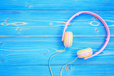 Mavi ahşap tahta arka plan üzerinde yeni pembe müzik kulaklık. S ile