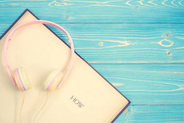 Kitap ve yeni modern pembe müzik kulaklık üzerinde mavi ahşap tahta ba