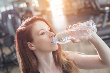 Spor salonunda egzersiz yaparken genç Kafkas kadın içme suyu