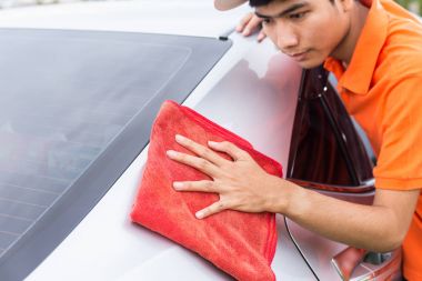 Genç adam yeni gümüş vücut temizliği kırmızı mikrofiber bez kullanarak