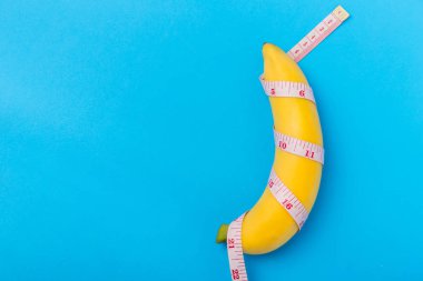 Sarı muz ölçüm bandı üzerinde mavi arka plan ile. Erkeklerin Pi