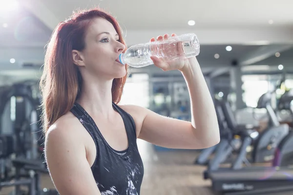 Spor salonunda egzersiz yaparken genç Kafkas kadın içme suyu