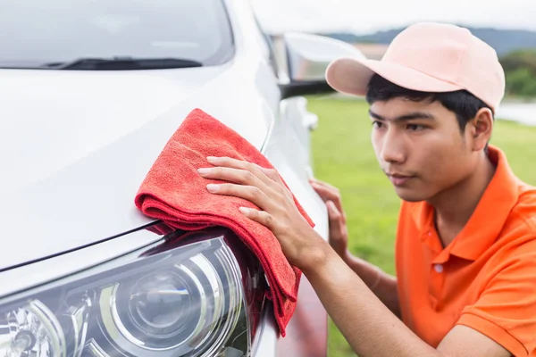 Jeune homme utilisant un chiffon en microfibre rouge corps de nettoyage de nouvel argent — Photo