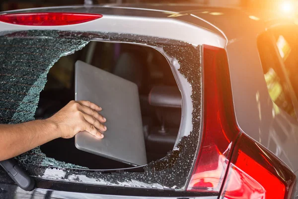 Mano que roba el ordenador portátil de la parte posterior del coche que brok cristal trasero — Foto de Stock