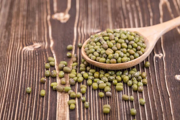 Mung beans in wooden spoon put on wooden plank background — Stock Photo, Image