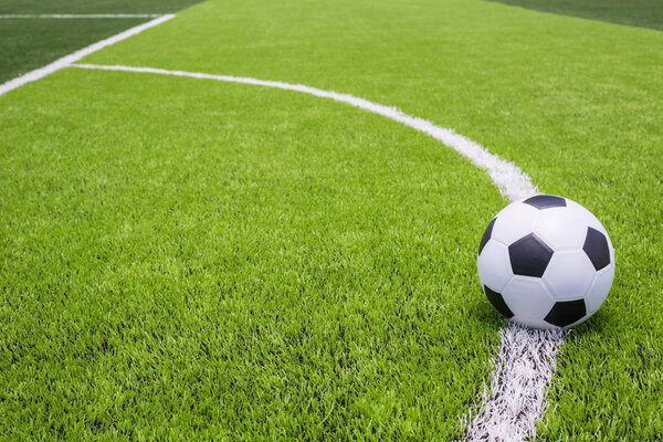 Футбольный мяч на искусственной яркой и темной зеленой траве на публике
 