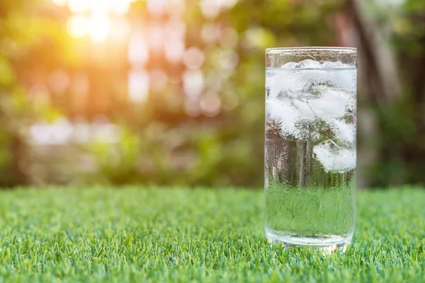 Vaso de agua fría con hielo en la mesa con desenfoque naturaleza jardín ba —  Fotos de Stock