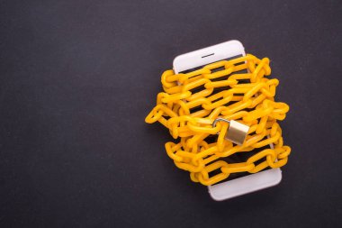 Kara taş tahta Smartphone'da çevresinde sarı zincir kilitli. 